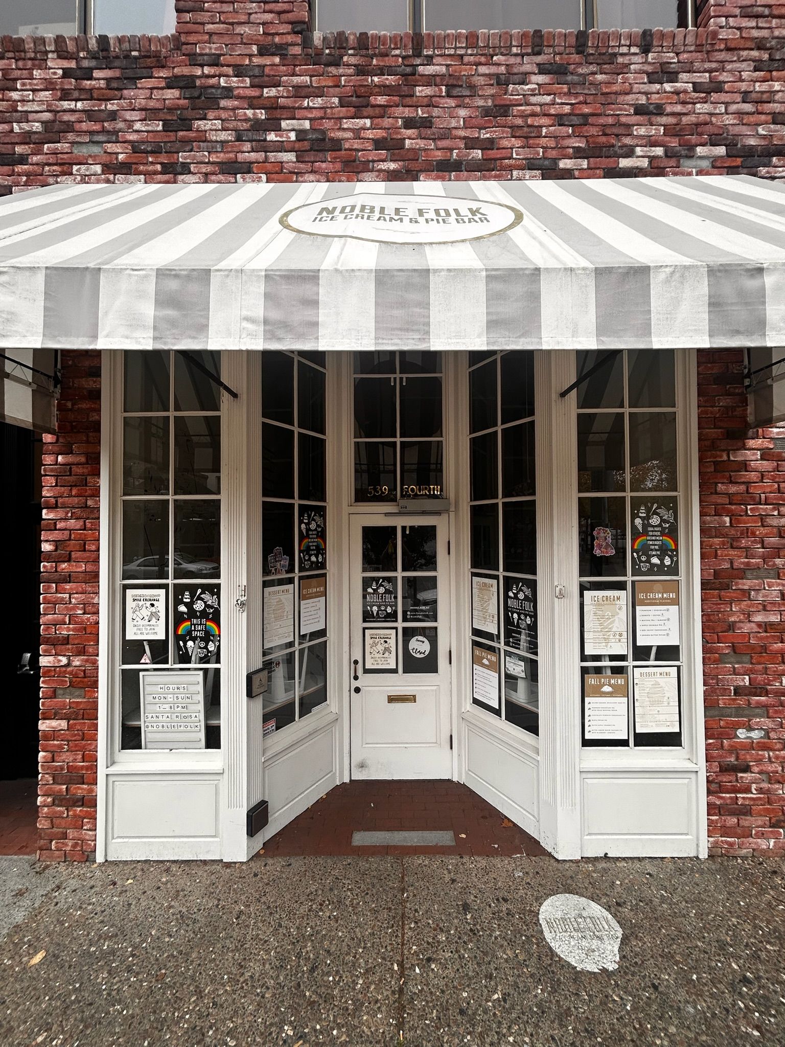 Storefront with white trim, brick facade, striped awning.