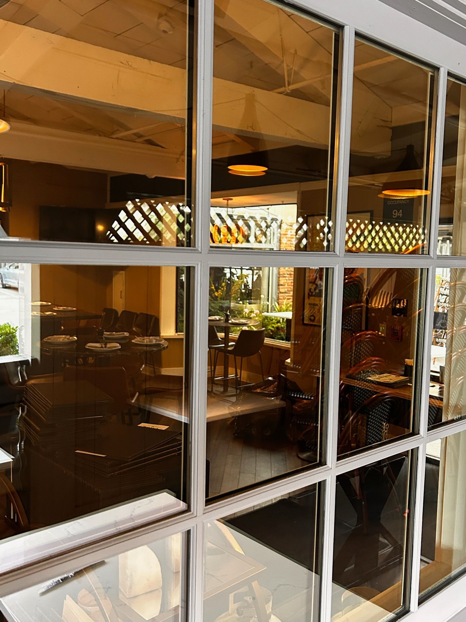 Window view into a restaurant with tables, chairs, and warm lighting.