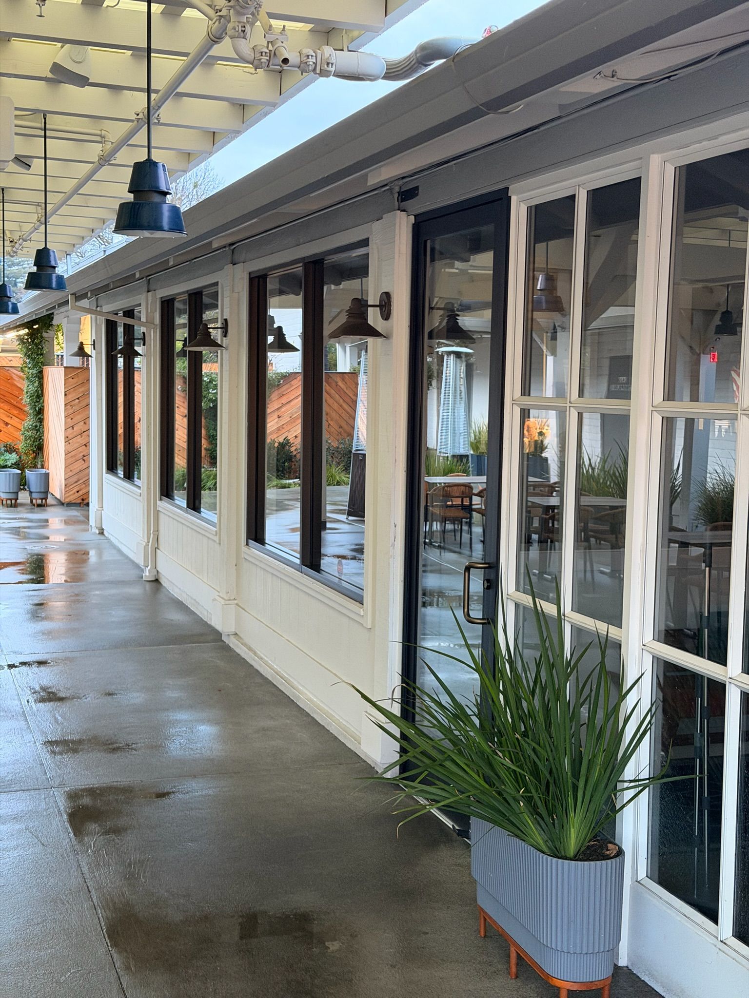 Exterior of a building with windows, a covered walkway, and potted plants.