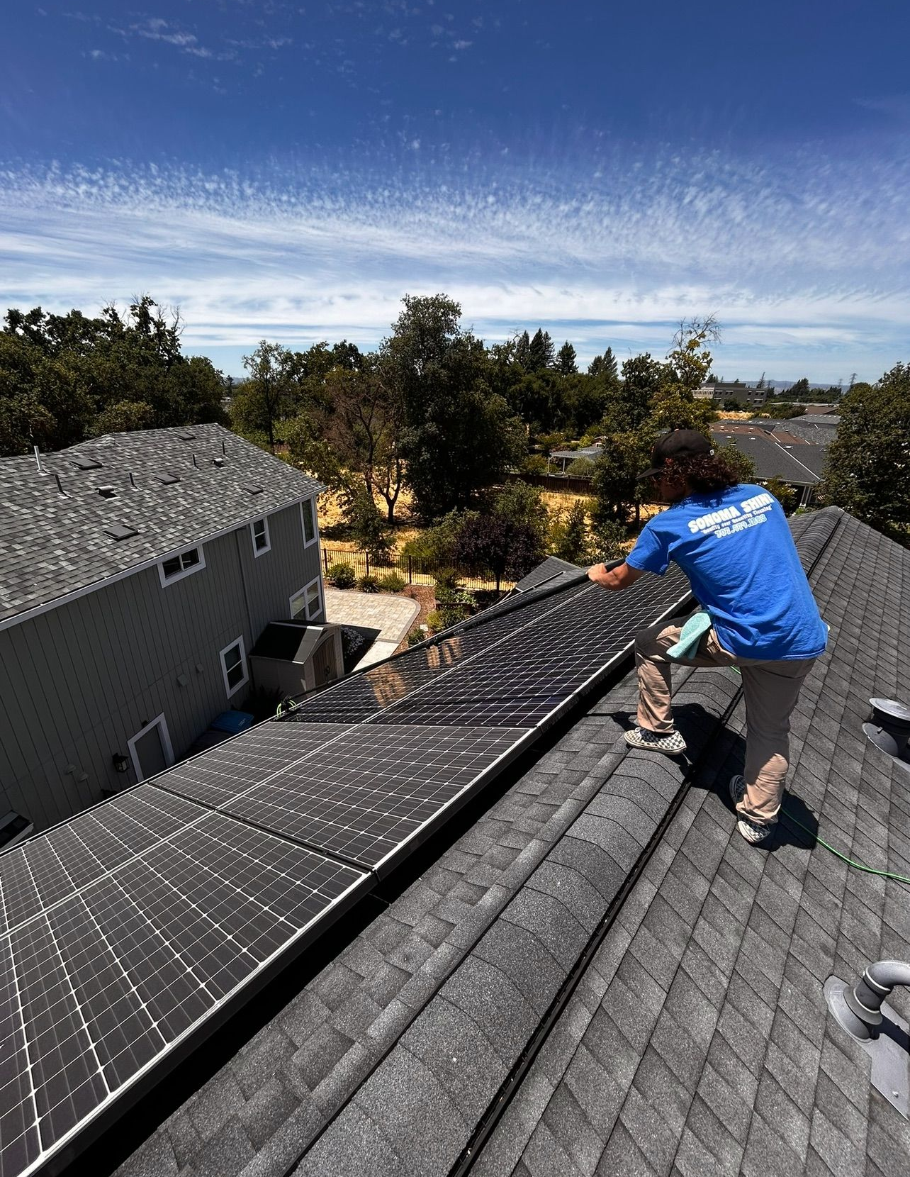 Person installing solar panels on a rooftop on a sunny day.