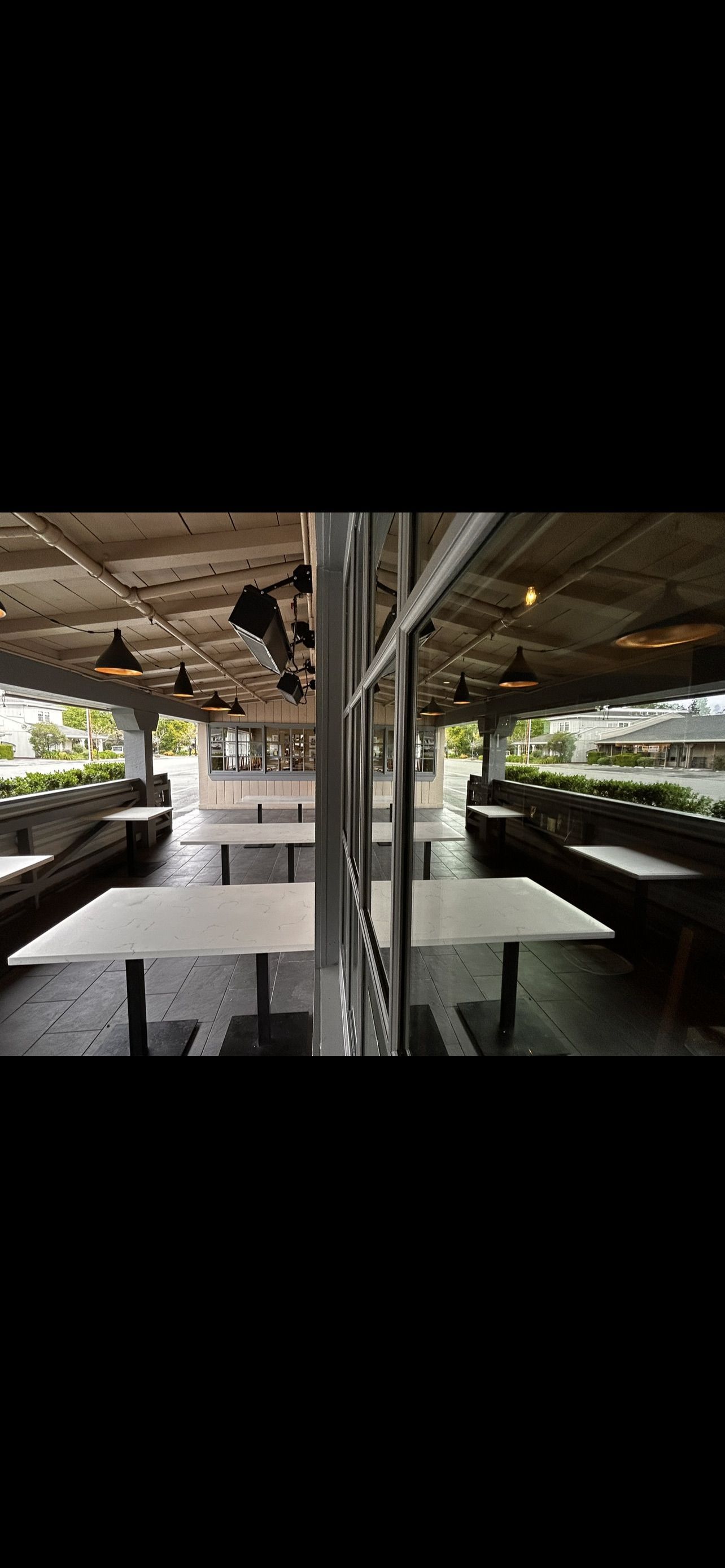 A covered outdoor dining area with tables and benches.