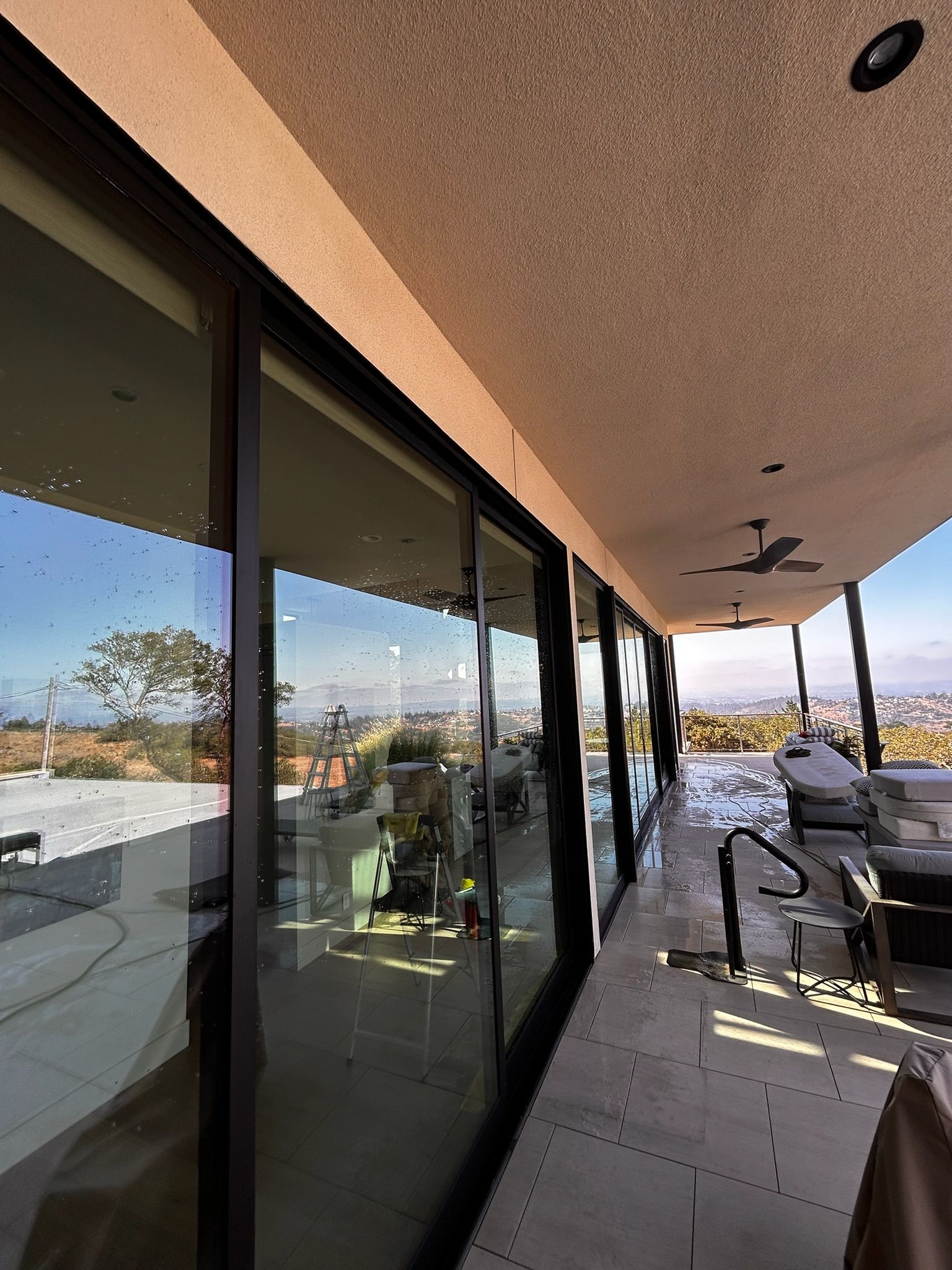 Glass sliding doors on a balcony with a view of a city, trees, and blue sky.