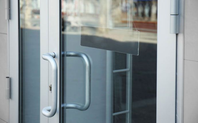 Glass door with silver handles. A blank black sign is visible on the glass.
