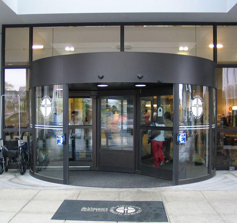 Entrance to a building with glass doors and a curved black canopy, bicycles parked at left.