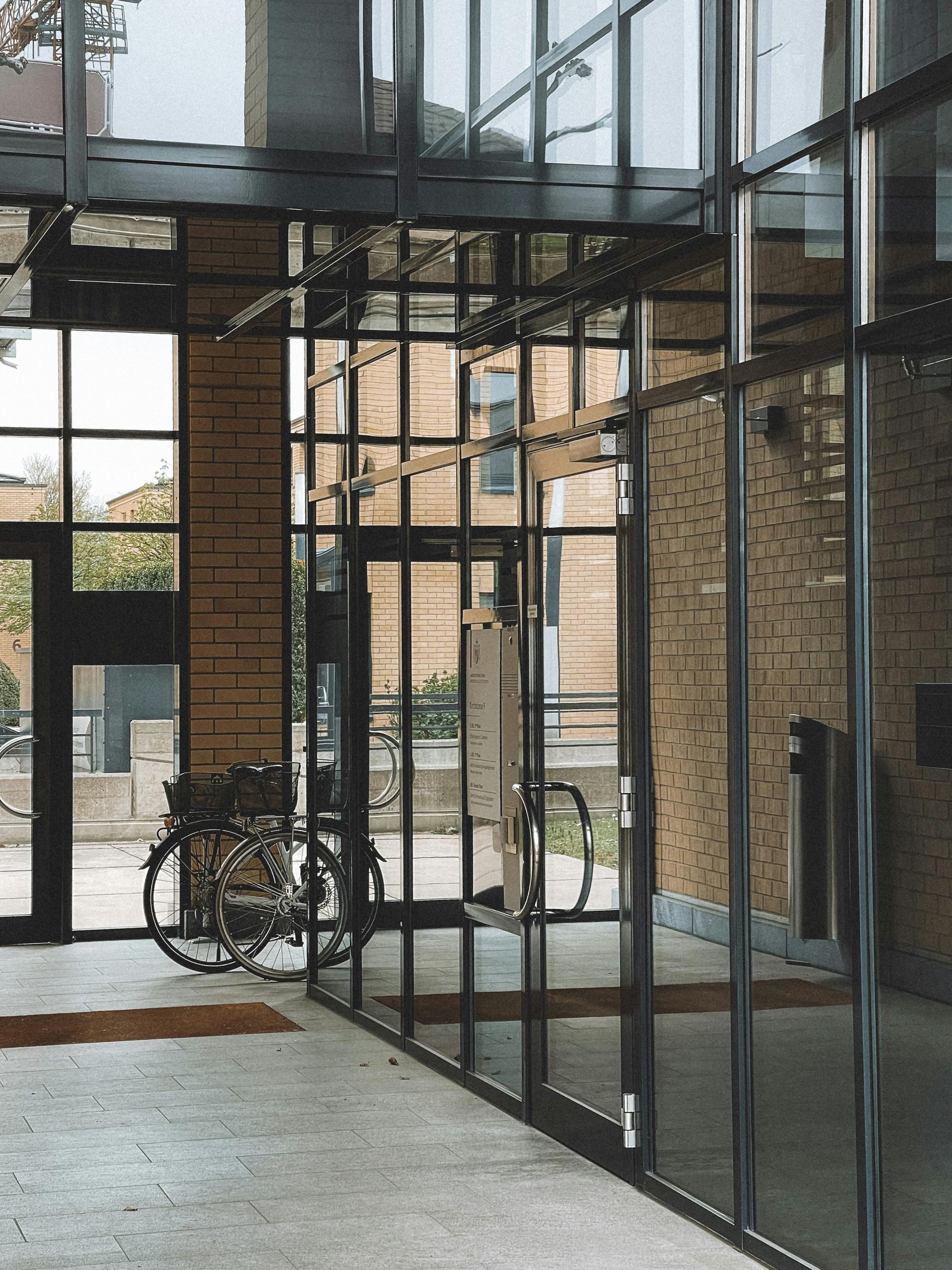 Glass-walled lobby with brick walls, concrete floor, and a bicycle near the entrance