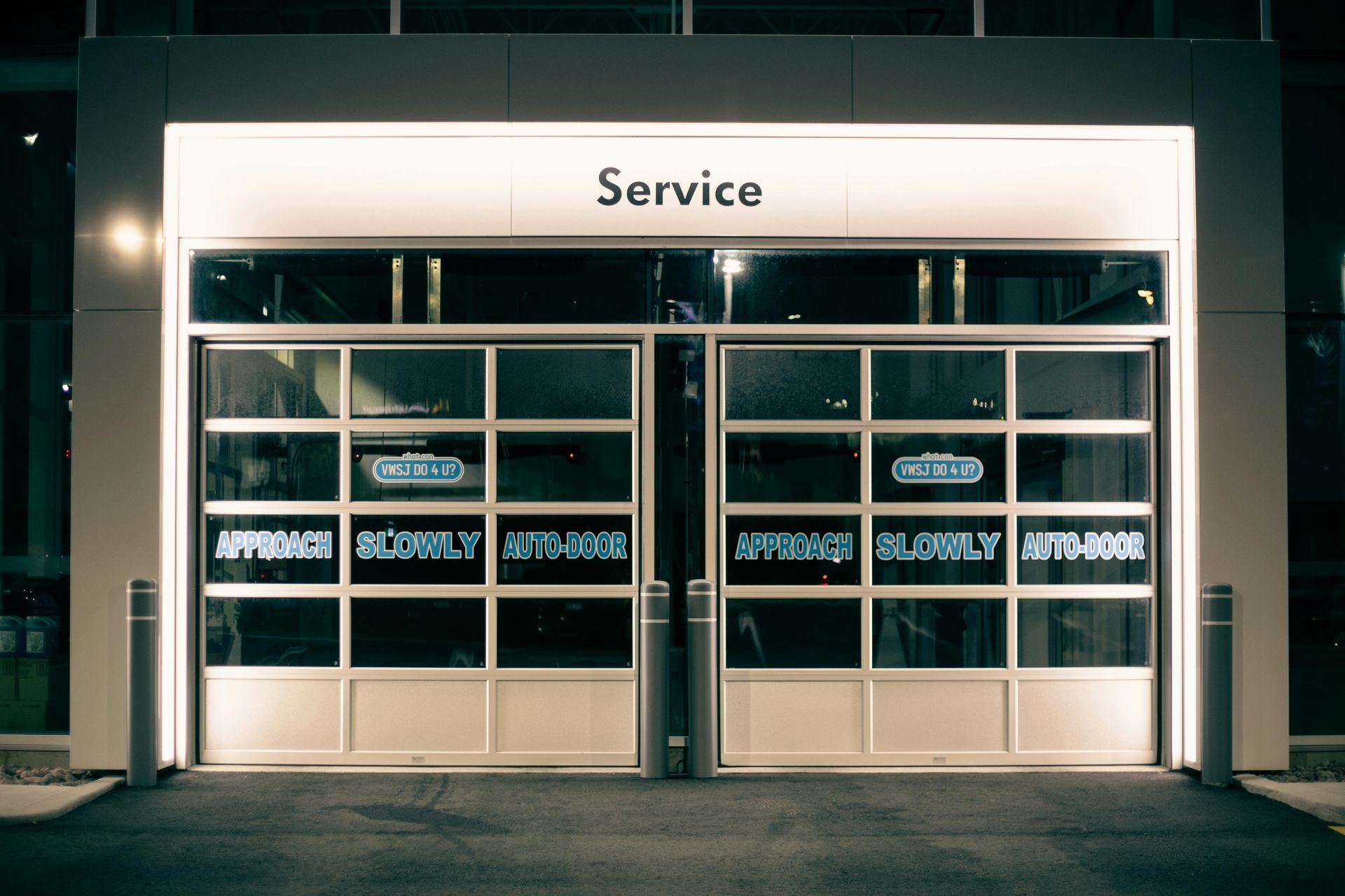Modern service garage with illuminated glass doors at night