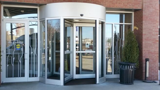 Building entrance with glass revolving door and side doors under a curved white canopy