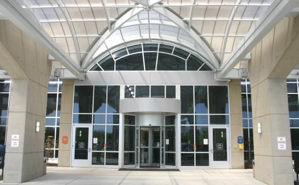 Glass doors with silver handles reflecting a building and trees.