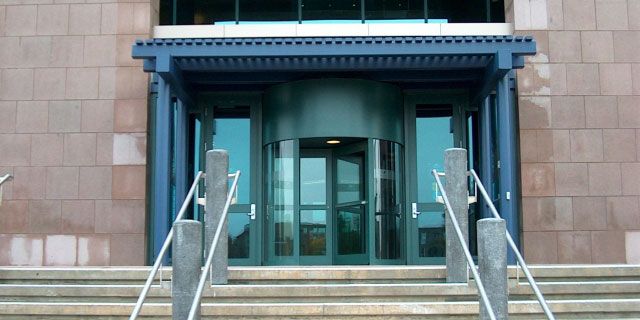 Front entrance with glass doors, blue awning, and stairs with metal handrails