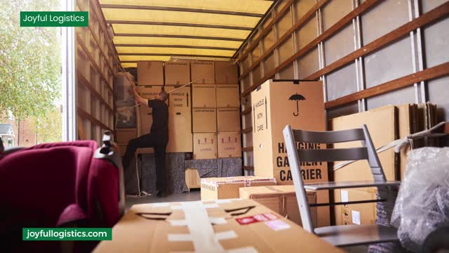 Boxes and furniture loaded inside a moving truck; a person is stacking boxes.