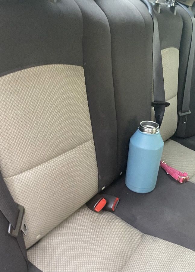 A blue water bottle is sitting on the back seat of a car.