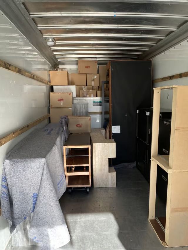 The inside of a moving truck filled with boxes and furniture