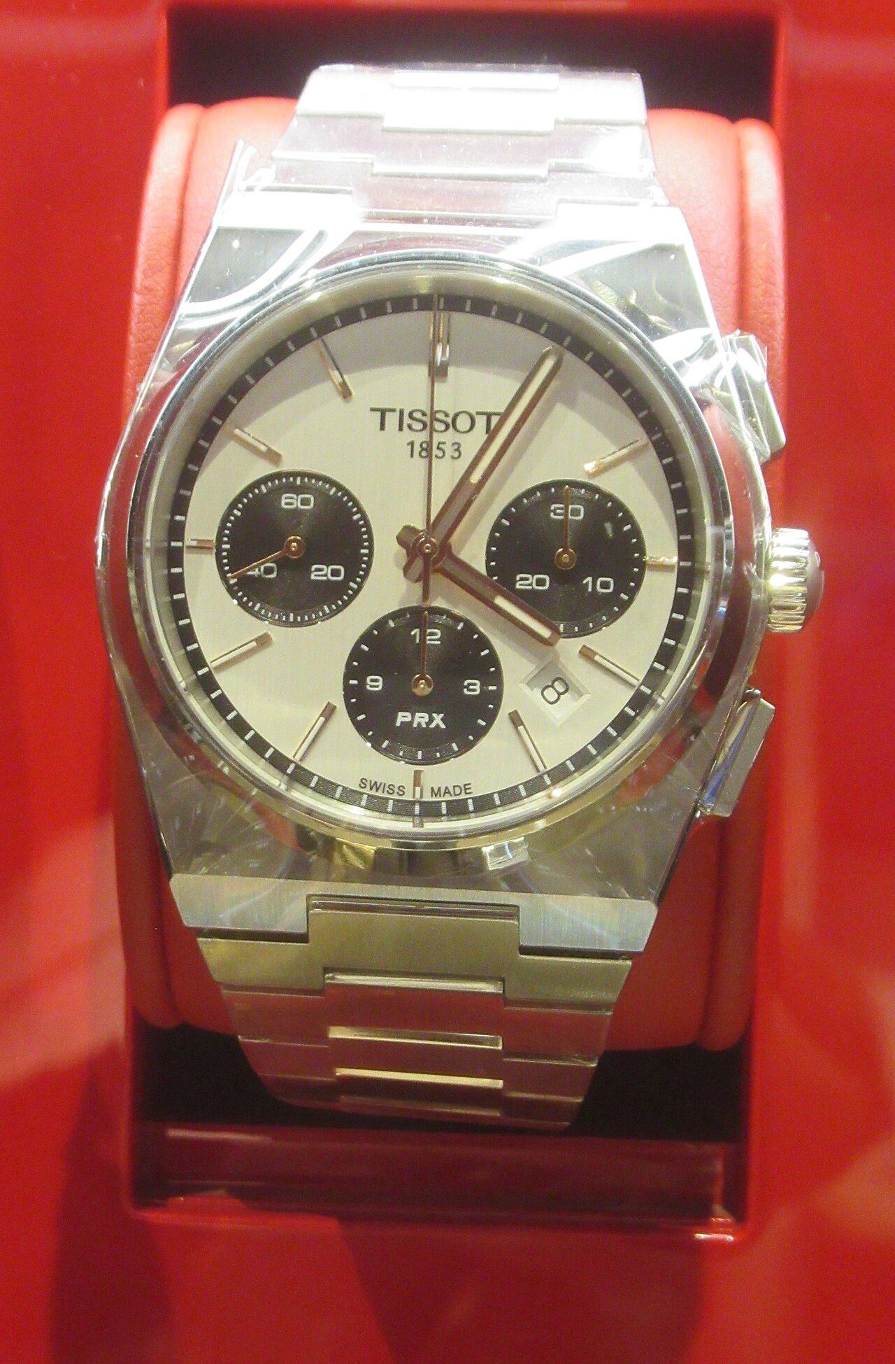 Tissot PRX chronograph in steel on a red display cushion, shown as an illustration of the PRX case and bracelet design
