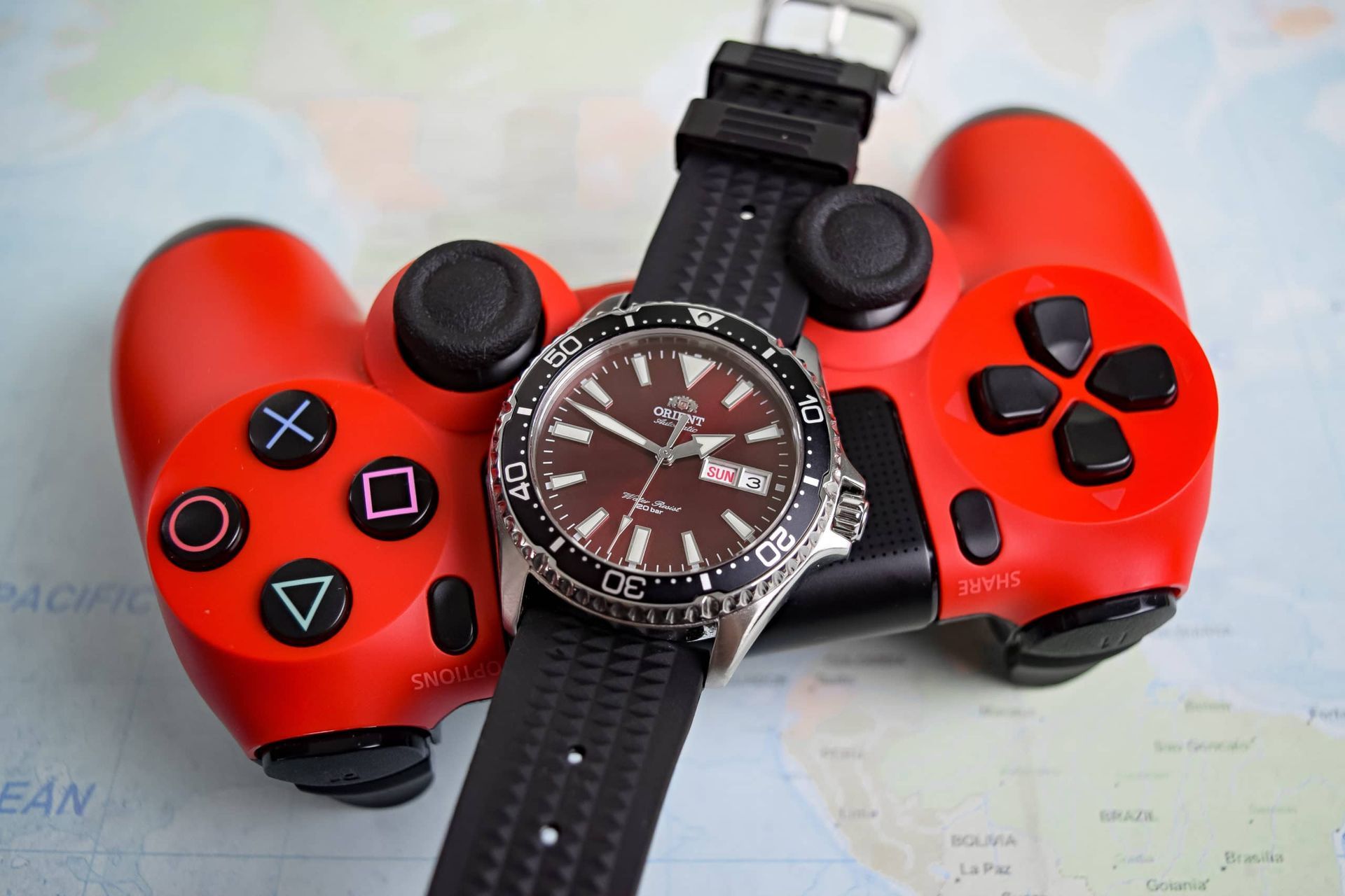 The Orient Kamasu with a red dial, showing its unidirectional bezel, polished and brushed case and day-date display.