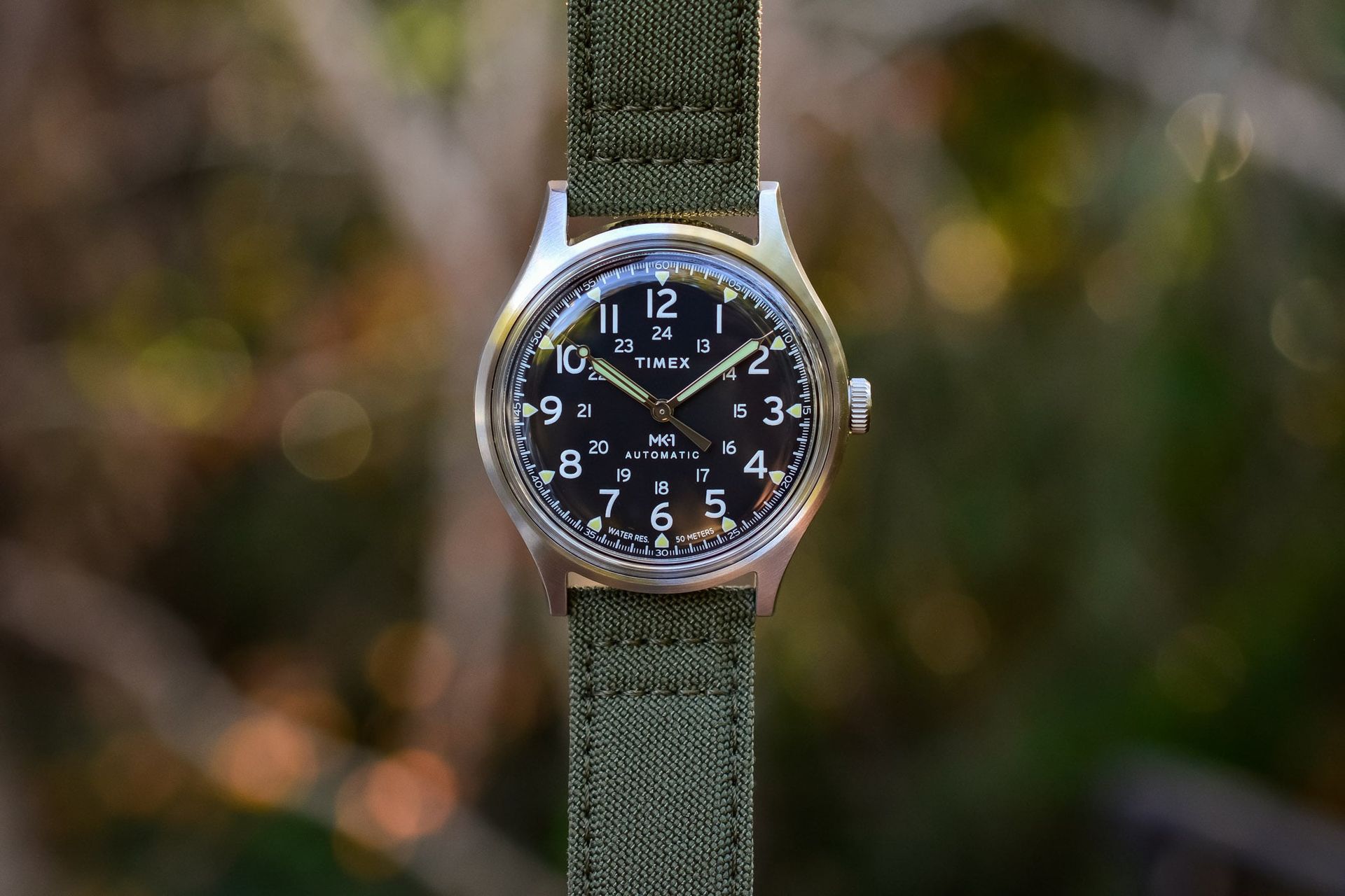 The Timex MK1 Automatic, with its 40mm steel case, box acrylic crystal, 12/24-hour field dial and green fabric strap.
