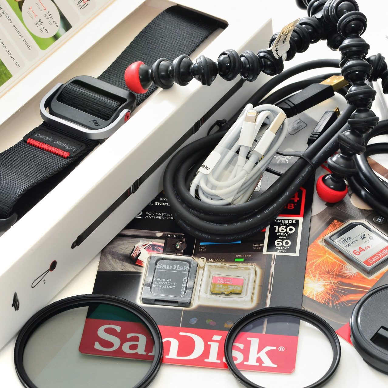 Eine sandisk-Karte liegt auf einem Tisch, mit Kabeln und Fotozubehör.