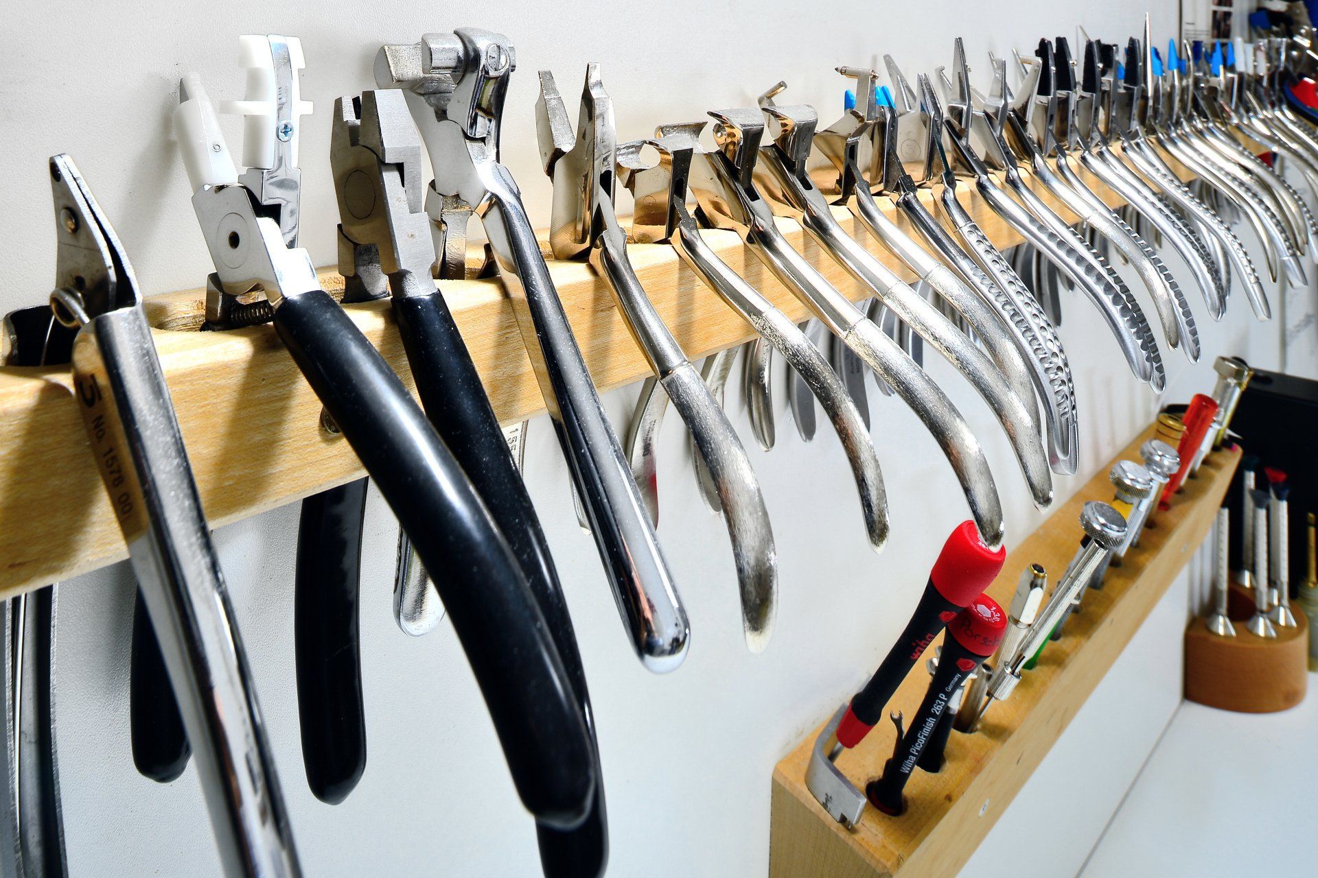 An einer Wand hängen mehrere Zangen, werkstatt augenoptiker