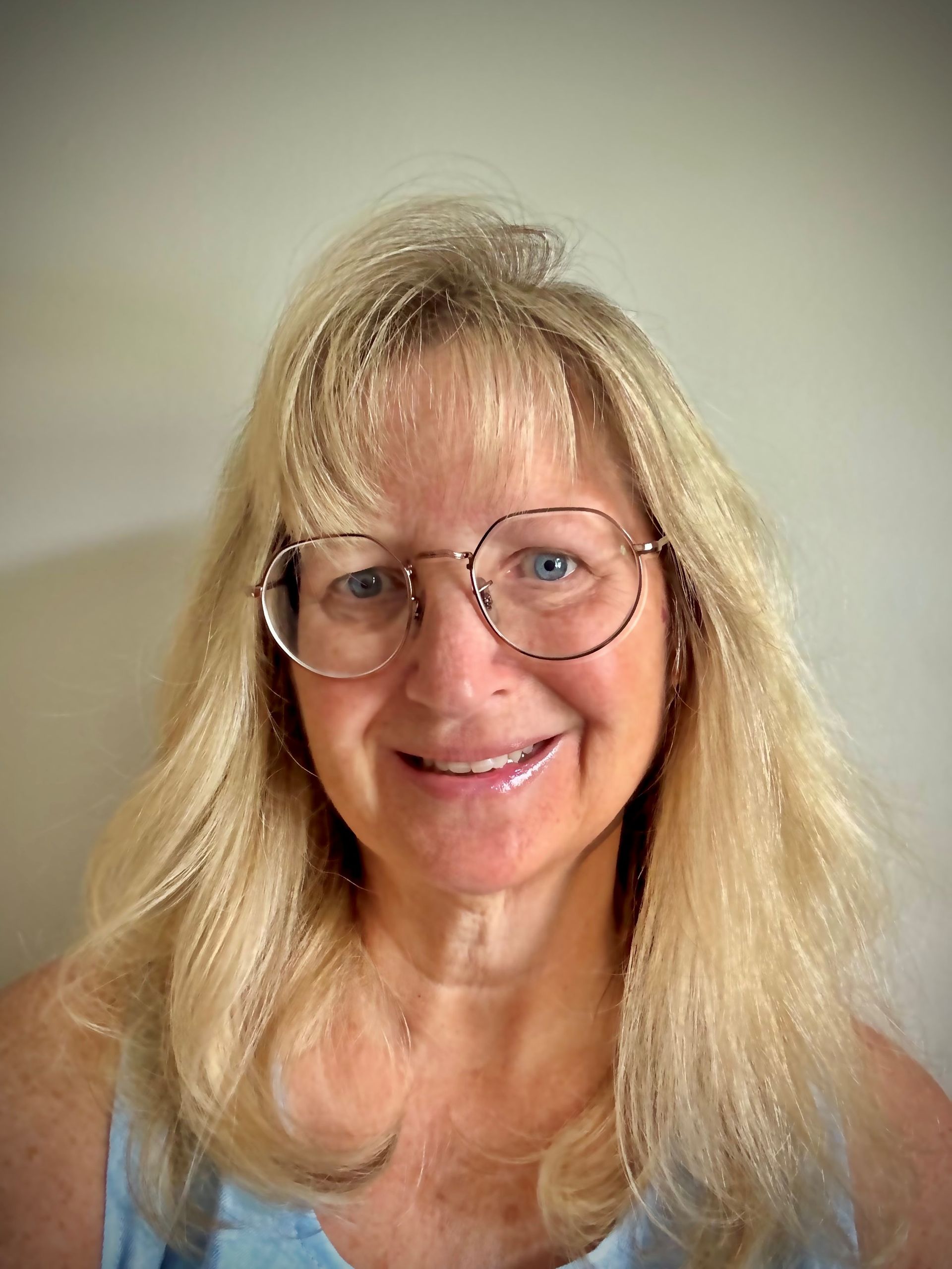 Woman with blonde hair, wearing glasses, smiling.