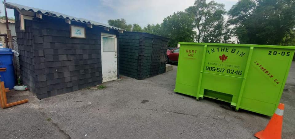 a green dumpster and a green portable toilet are parked next to each other .