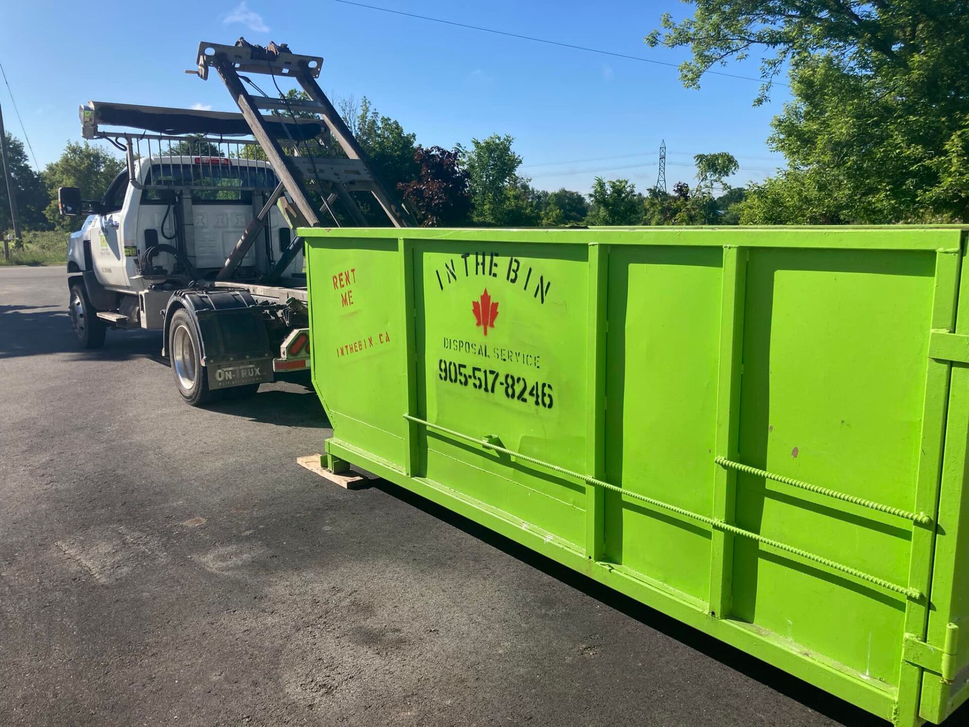 A truck unloading a green bin