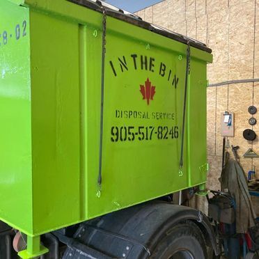 Green dumpster on a truck, with