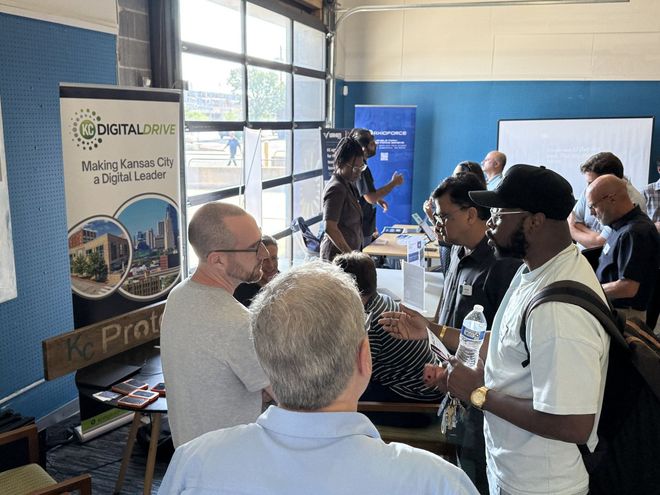 Attendees talking with exhibitors at the KC Digital Drive and KCProto tables during a Kansas City AI Club expo