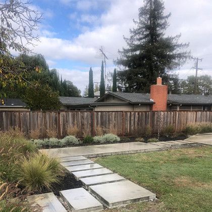 A house with a wooden fence and a walkway leading to it.