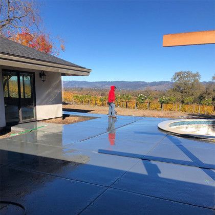 A man in a red hoodie is standing on a patio next to a house.