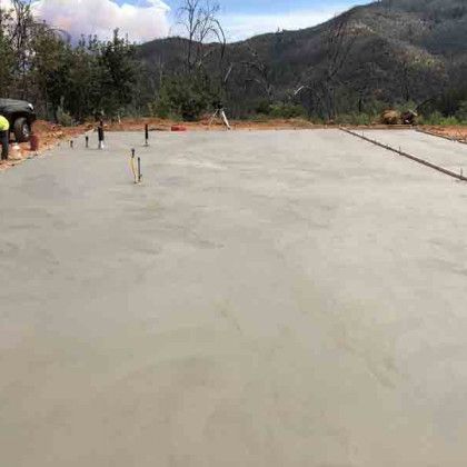 A concrete foundation is being built with mountains in the background.