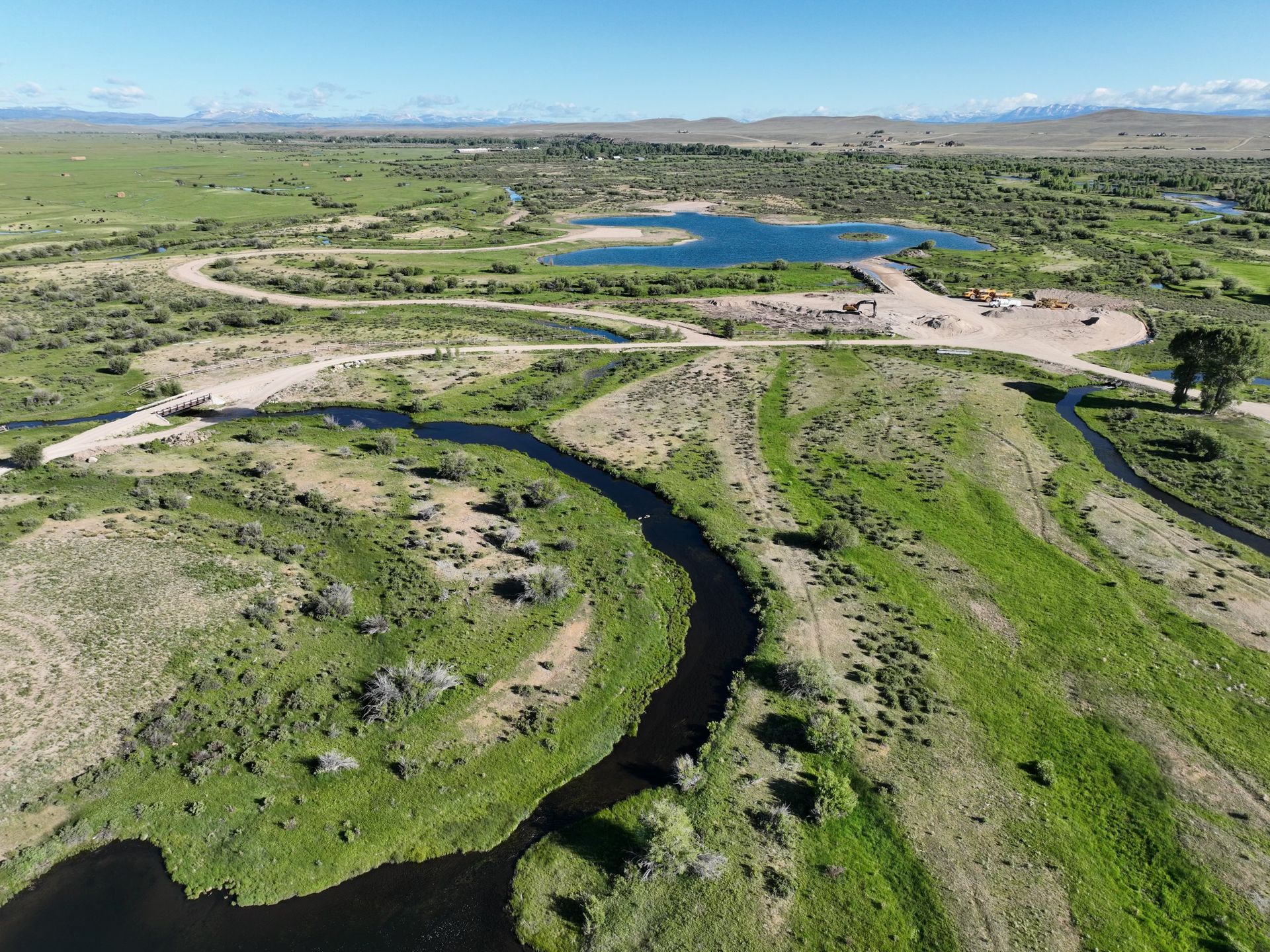 An aerial view of a river in the middle of a grassy field.
