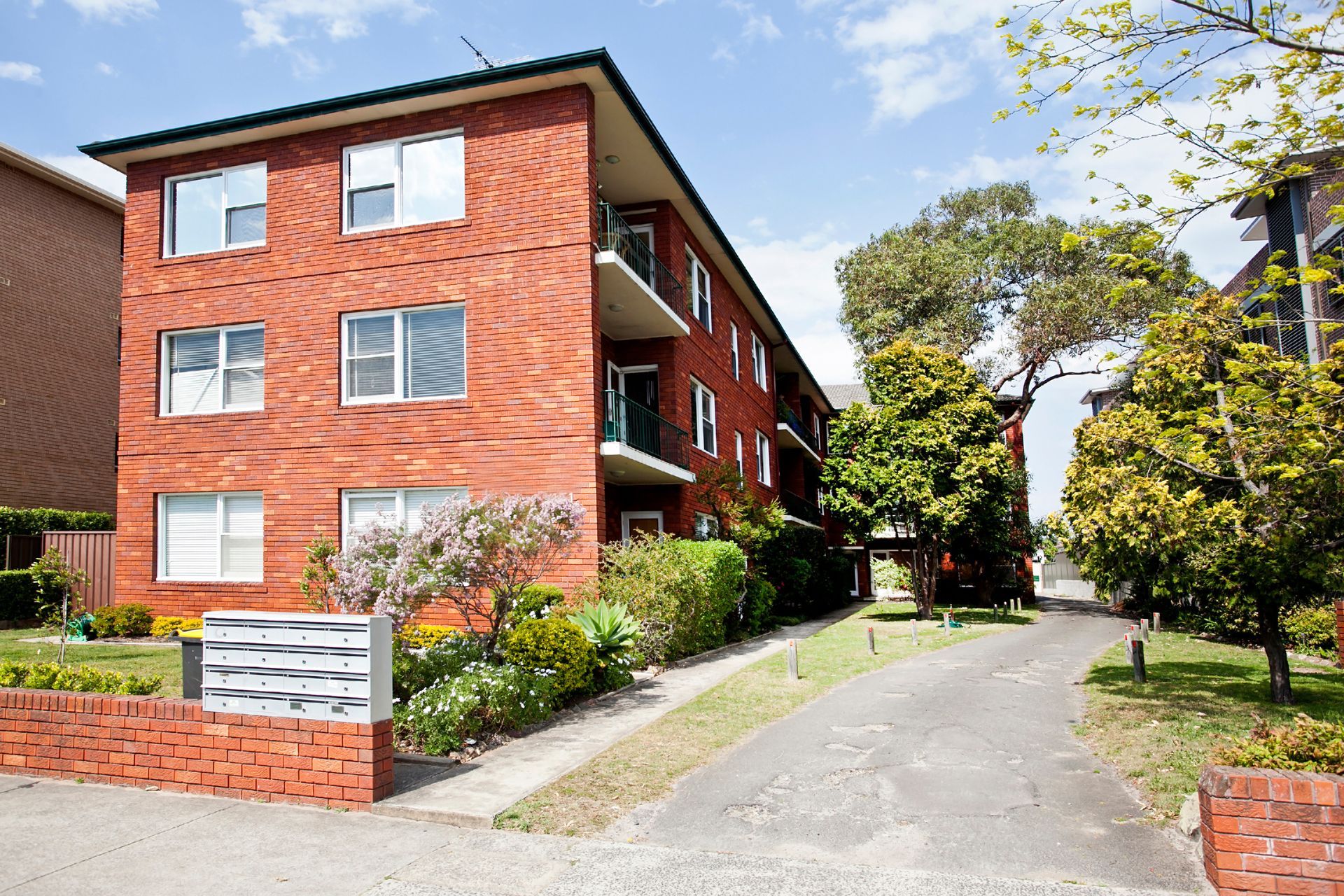 A brick apartment building with a driveway leading to it