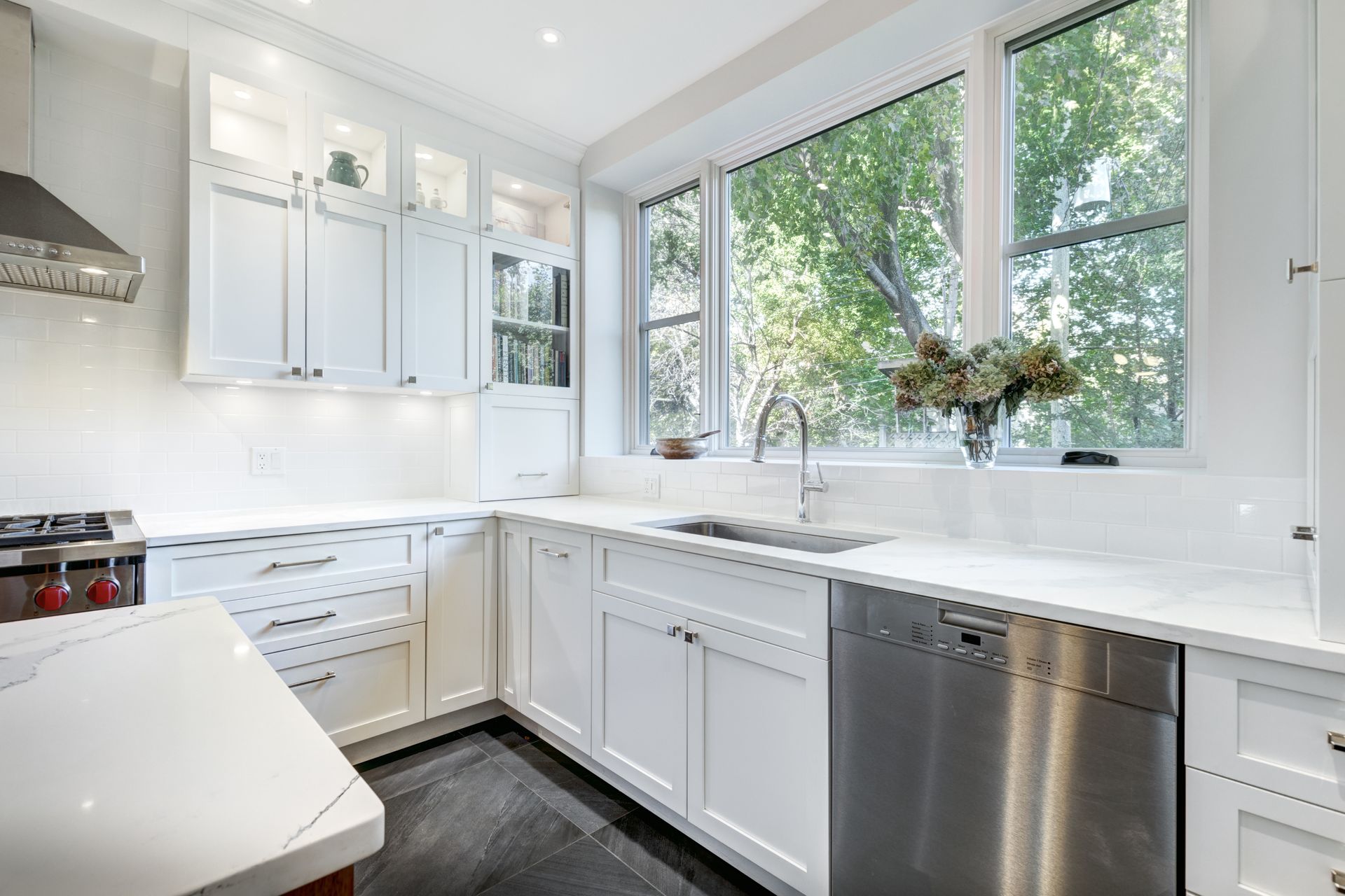 A kitchen with white cabinets , stainless steel appliances , and a large window.