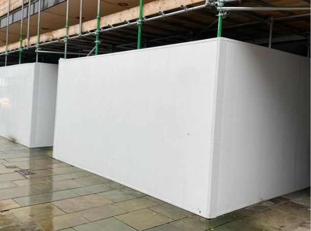 A building under construction with white walls and scaffolding.