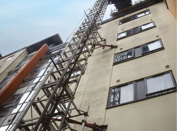 Looking up at a tall building with a ladder attached to it