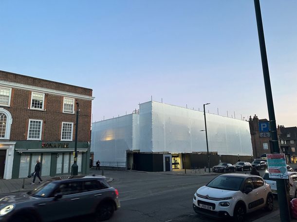 A large building is covered in white tarps and scaffolding.