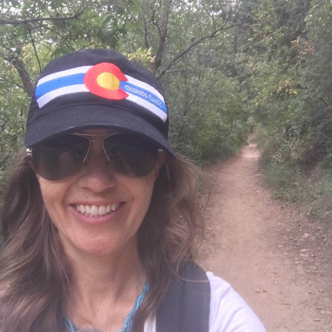 Mindy Sink hiking outdoors wearing Colorado cap