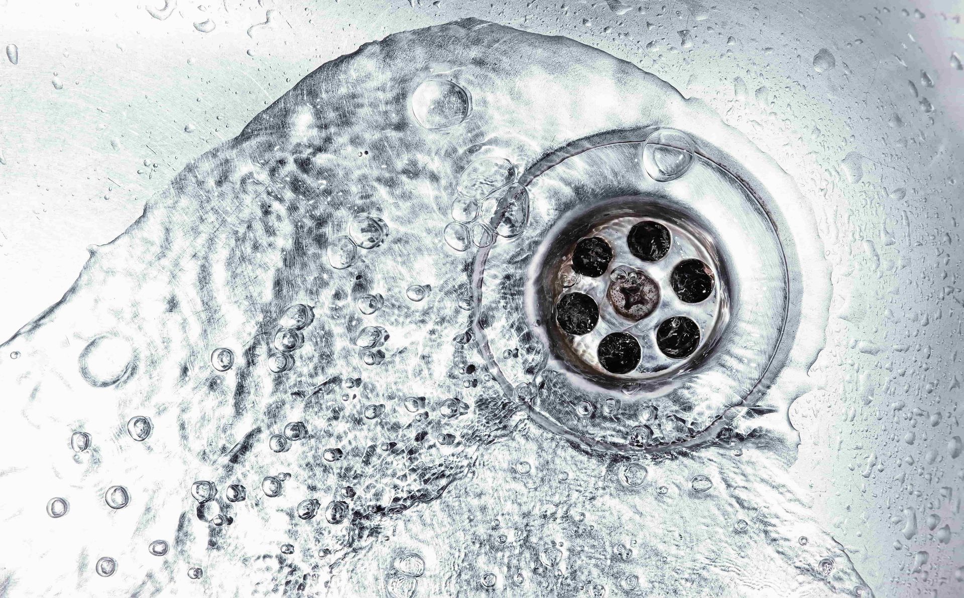 A close up of a sink drain with water coming out of it.
