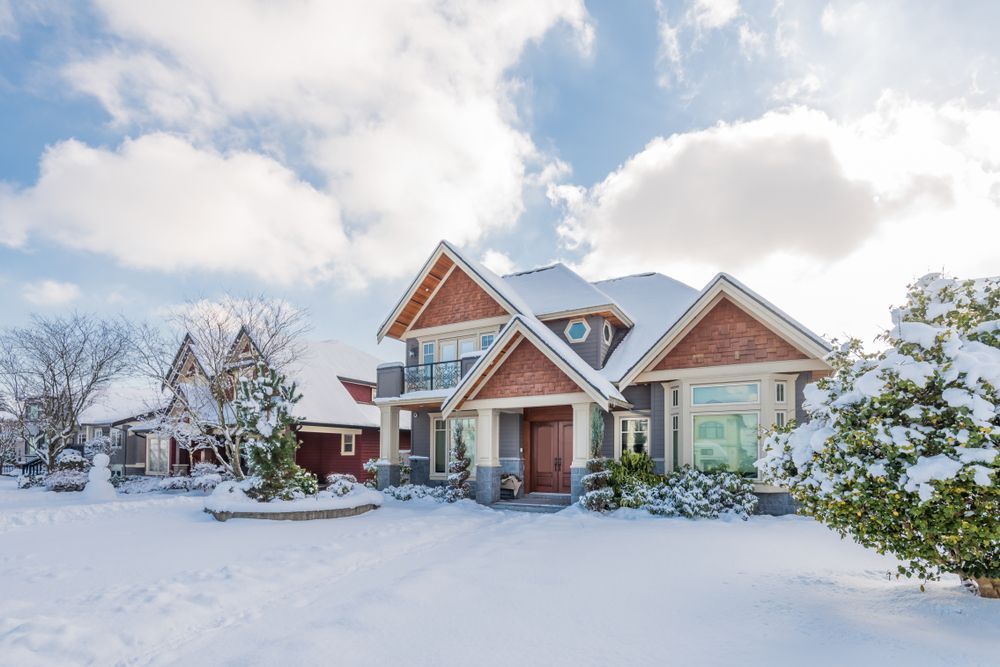 A large house is covered in snow in a snowy neighborhood.