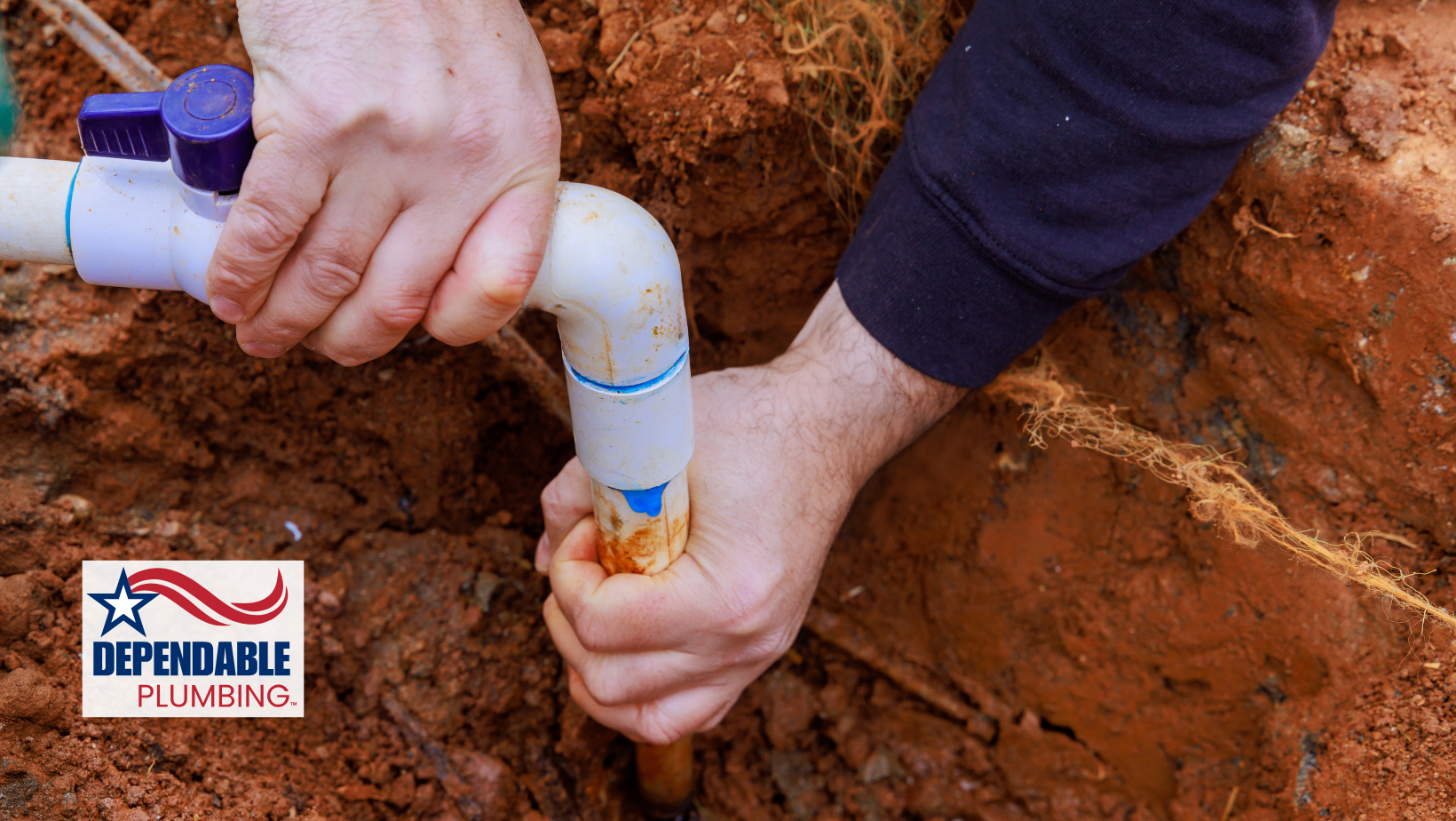 Hands connecting white PVC pipe fittings in a trench. Blue valve visible. Earth background.