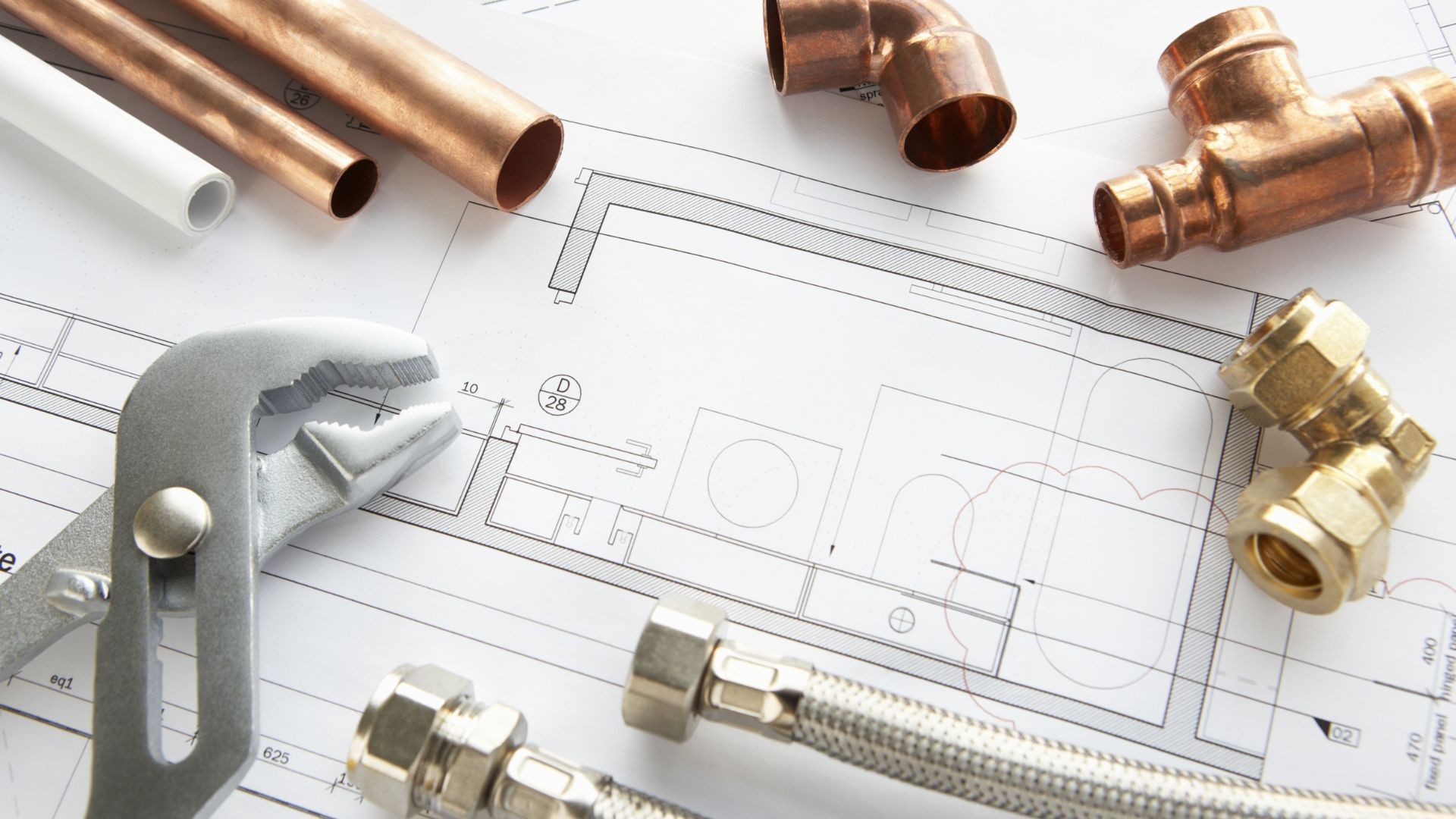 Plumbing tools and fittings on top of a blueprint.