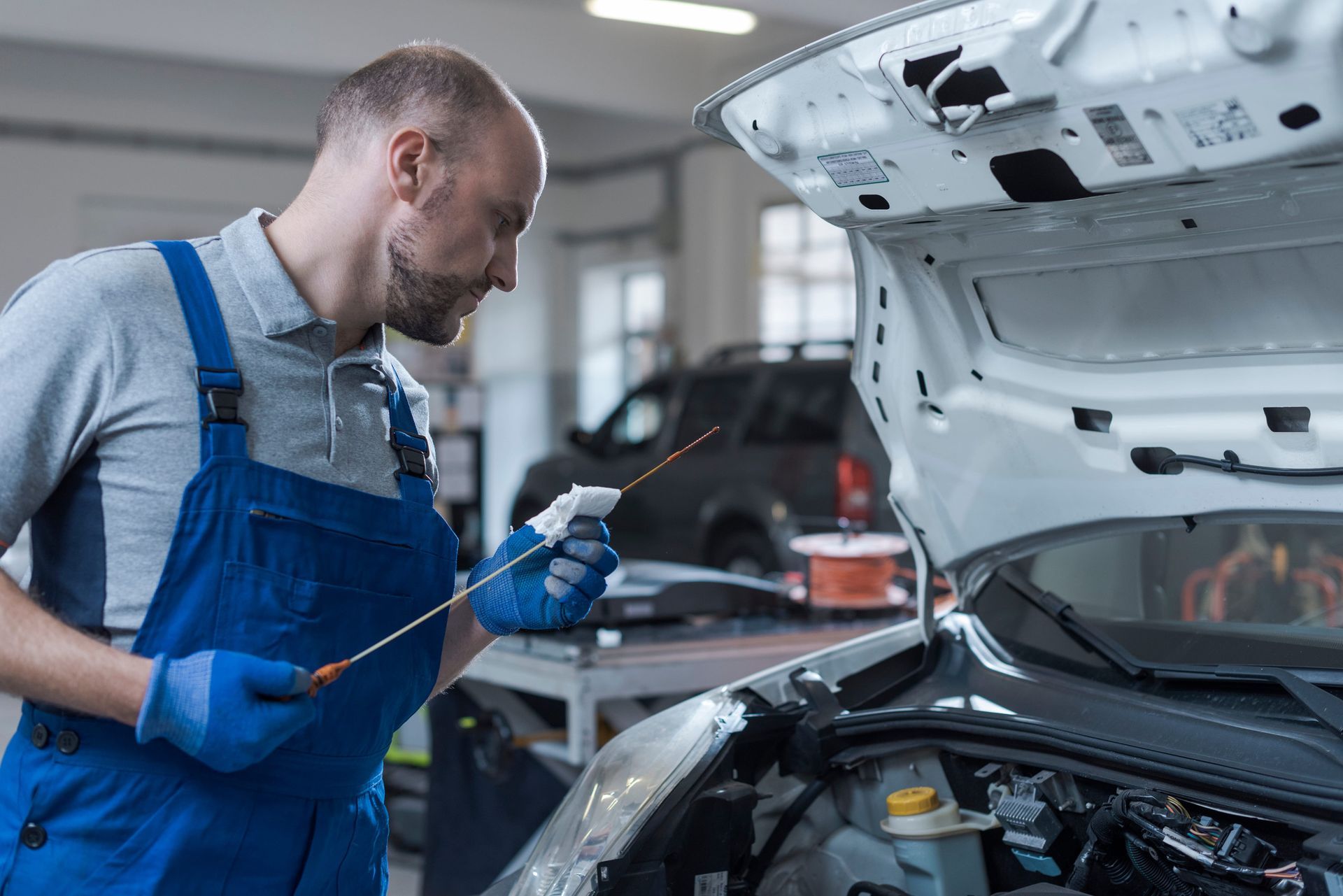 Mechanic checking the engine oil level with a dipstick during a factory scheduled maintenance inspec