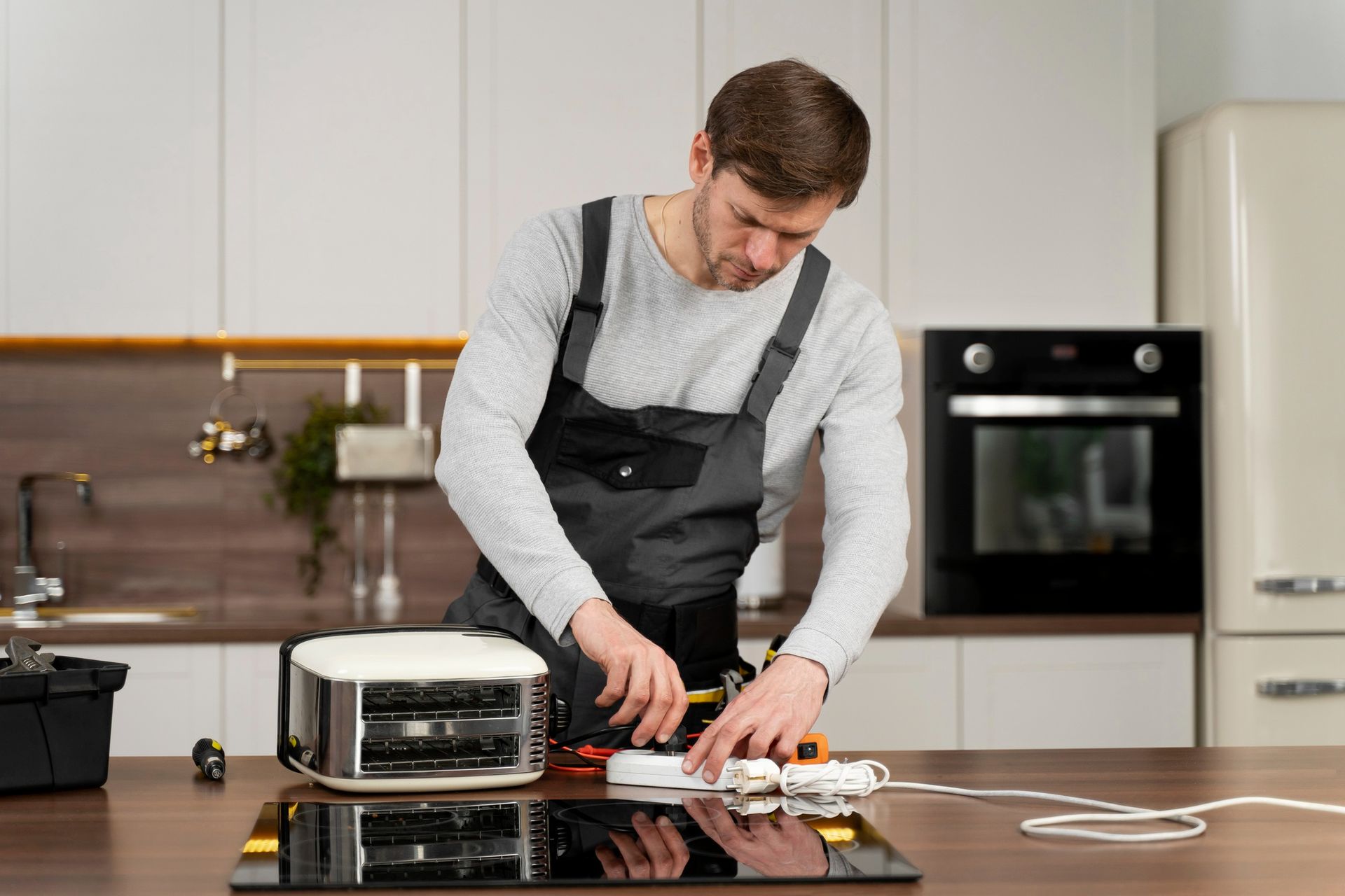 A man is fixing a toaster oven in a kitchen.