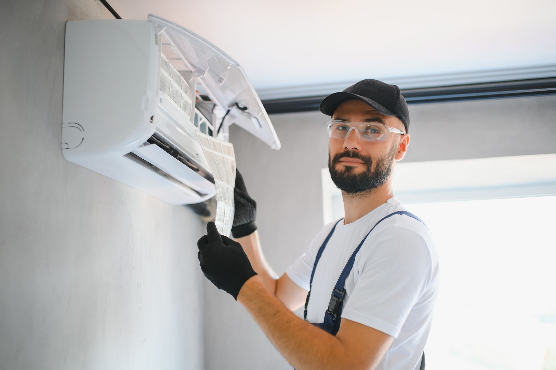 A man is fixing an air conditioner on the wall.