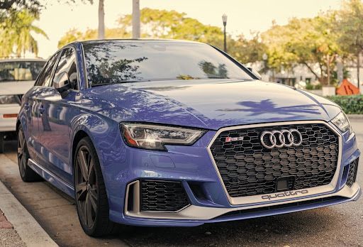 Front view of a blue Audi RS3 parked outdoors, highlighting the distinctive grille and performance s