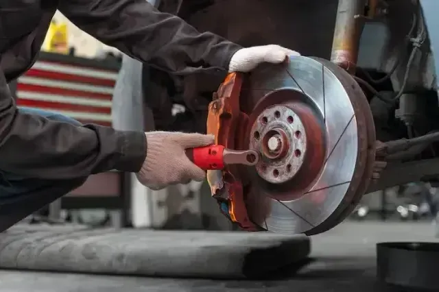 A man is working on the engine of a car in a garage.