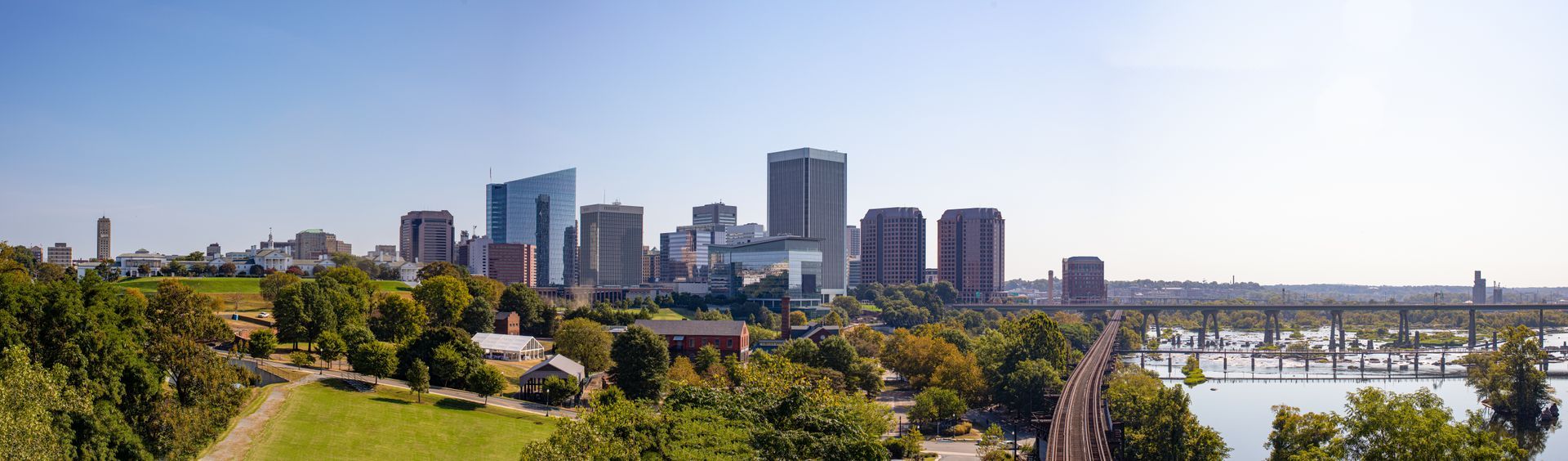 Skyline of Richmond, Virginia, with a view of the James River and a bridge under a blue sky.
