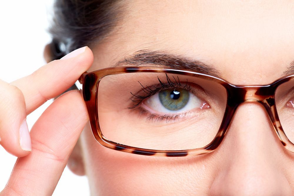 Woman wearing glasses, adjusting frame with fingers; green eyes, brown tortoiseshell glasses  — Eyepower In Tahmoor, NSW