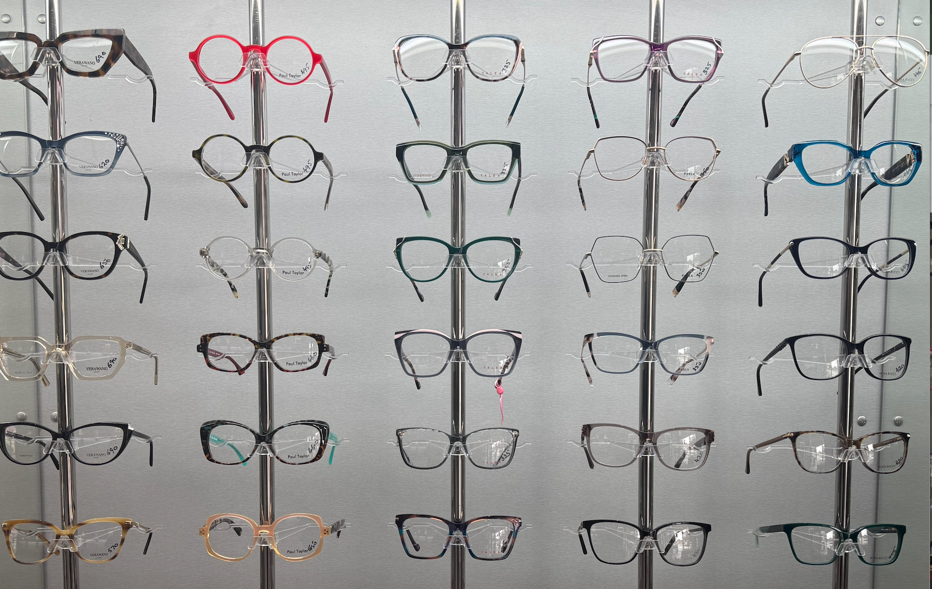 Glasses on display in a store, in various shapes, sizes and colours, against a frosted glass background  — Eyepower In Tahmoor, NSW