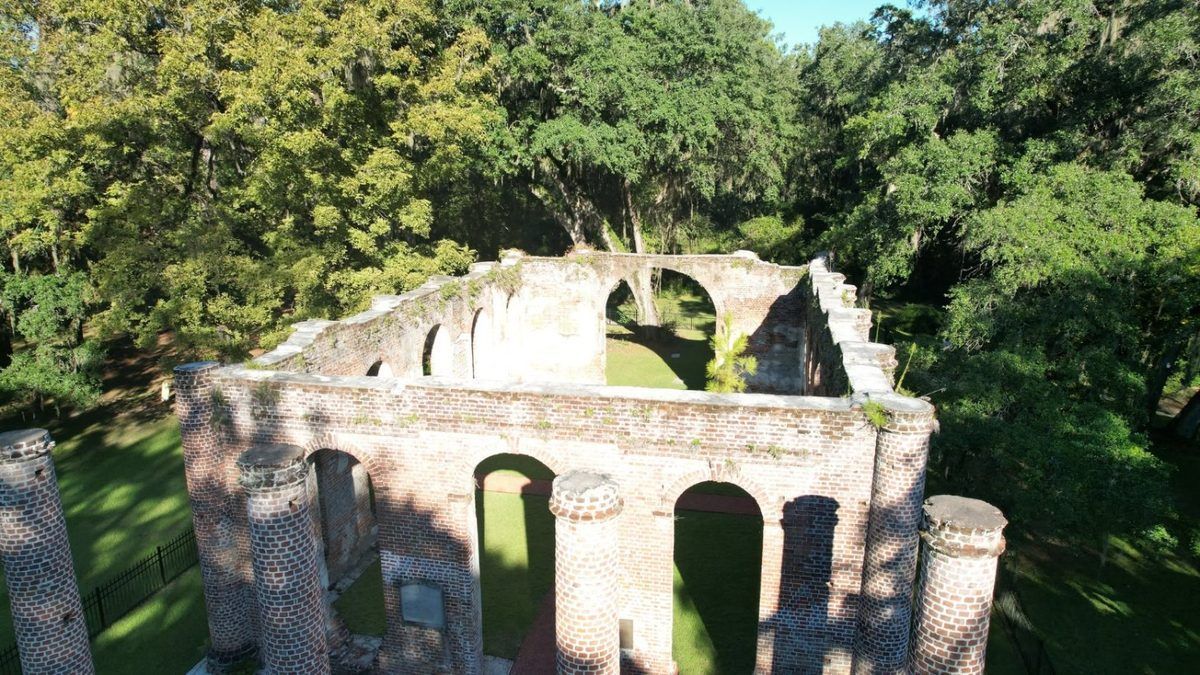 Drone photo of historic brick church ruins and columns among oak trees