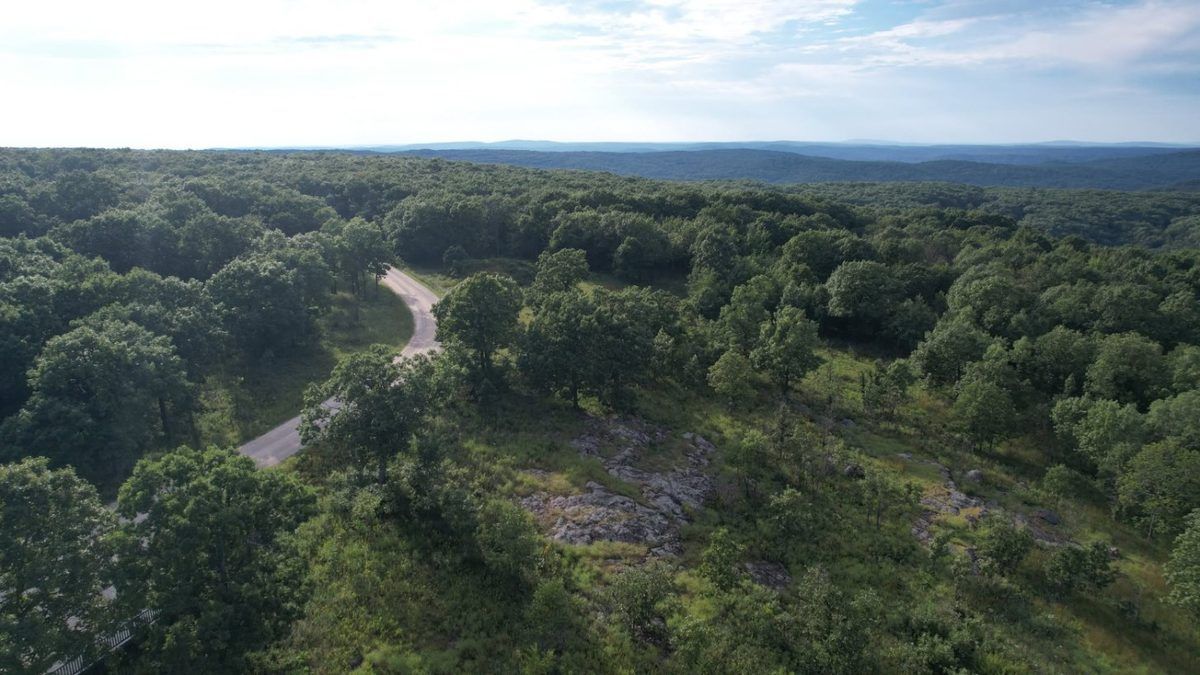 Aerial drone photo of a winding road through a forested ridge